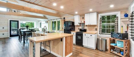 Una cocina moderna con suelo de madera, armarios blancos, una isla central y un comedor con sillas.