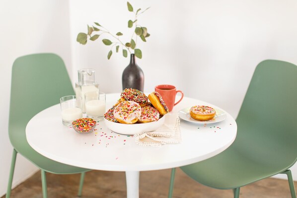 A round white table with a bowl of donuts and a red mug.