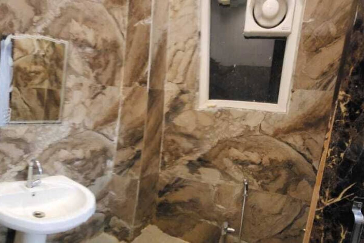 A bathroom with a marble wall, a sink, and a mirror.