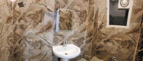 Un baño con pared de mármol, un lavabo y un espejo.