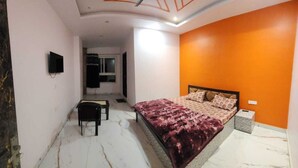 A bedroom with a bed, a chair, a desk, and a television. - Hotel Vrindavan (Unnao)