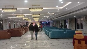 A spacious hall with rows of chairs, a marble floor, and chandeliers. - Hotel Vrindavan (Unnao)