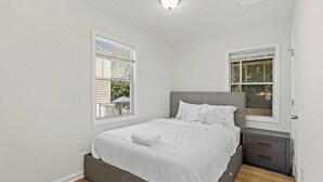 A bedroom with a single bed, a nightstand, a window with blinds, and a ceiling light. - Sultan MAIN · Metro | Location | Convenience | Budget | 3 queen (Capitol Heights)