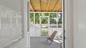A covered porch with a wooden ceiling, a white door, and a wooden chair. - Sultan MAIN · Metro | Location | Convenience | Budget | 3 queen (Capitol Heights)