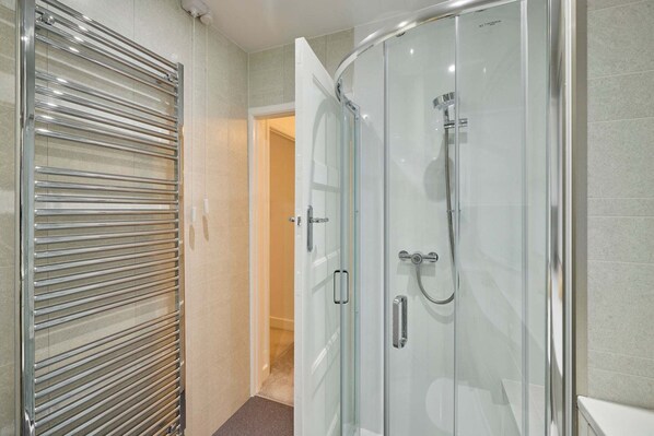 A modern bathroom with a glass shower enclosure, a glass door shower, and a towel rack. - Host Stay Sea Haven (Redcar)