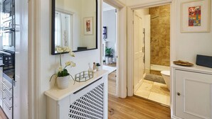 Une salle de bain moderne avec une douche, un lavabo et des toilettes. Un miroir est placé au-dessus du lavabo et une plante en pot se trouve sur le comptoir.