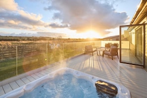 A hot tub on a wooden deck with a glass railing, overlooking a field. - Host Stay Hazelwood Deluxe Lodge (Hexham)