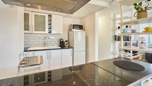 A modern kitchen with white cabinets, a built-in microwave, a coffee machine, and a black countertop. - Host Stay St James Street (Brighton)