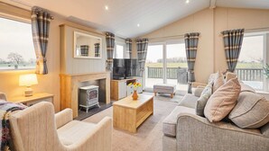 A spacious living room with a fireplace, comfortable seating, a flat-screen TV, and large windows with curtains. - Host Stay Portland 1 (Hexham)