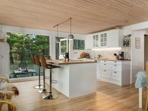 Una cocina moderna con armarios blancos, una isla central y taburetes de bar.