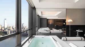 A modern hotel room with a large city view, a spa area with a bathtub, and a dining area with a lamp. - INDITION Chongqing Jiangbeizui Financial (Chongqing)