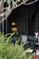 Un área de estar al aire libre con un letrero del Hotel Indition, que presenta un diseño moderno con sillas de patrón blanco y negro y una mesa de vidrio.