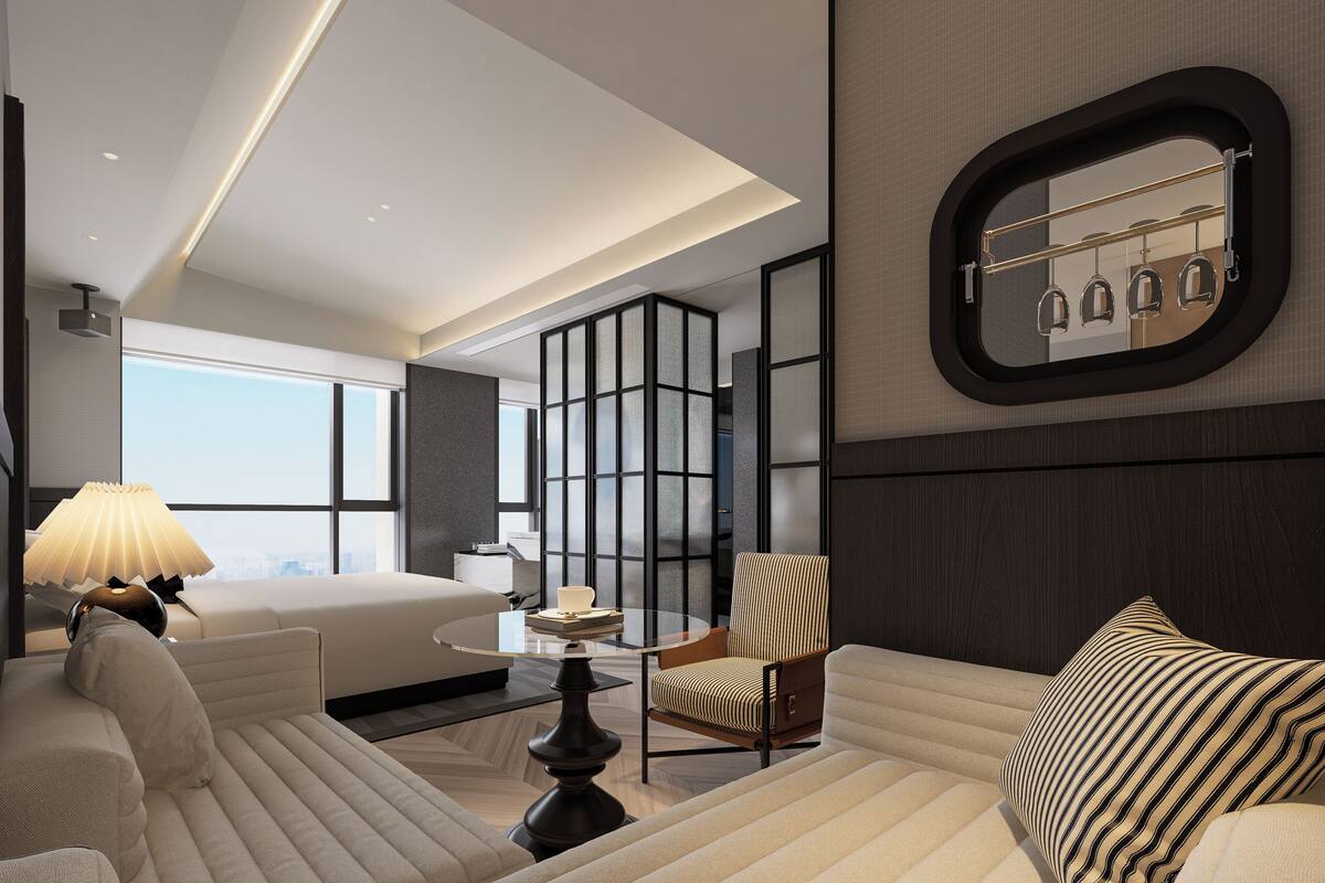 Een moderne hotelkamer met een groot bed, een bank, een stoel, een bijzettafeltje en een groot raam met uitzicht op de stad.