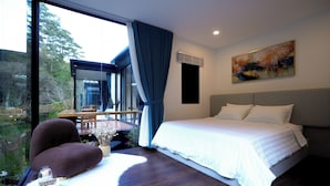 Un dormitorio moderno con una cama grande, vista a un comedor y un cuadro en la pared.