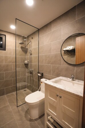 A modern bathroom with a glass-enclosed shower, a toilet, a sink with a marble countertop, and a wooden cabinet. - Kiwuki Dalat Resort (Lang Biang - Da Lat)