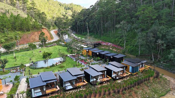 Un resort moderno con varias cabañas, una piscina y un jardín exuberante.