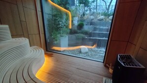 A modern room with a wooden floor, a curved sofa, a glass door leading outside, and a small heater. - One room apartment  (Saints Constantine and Helena)