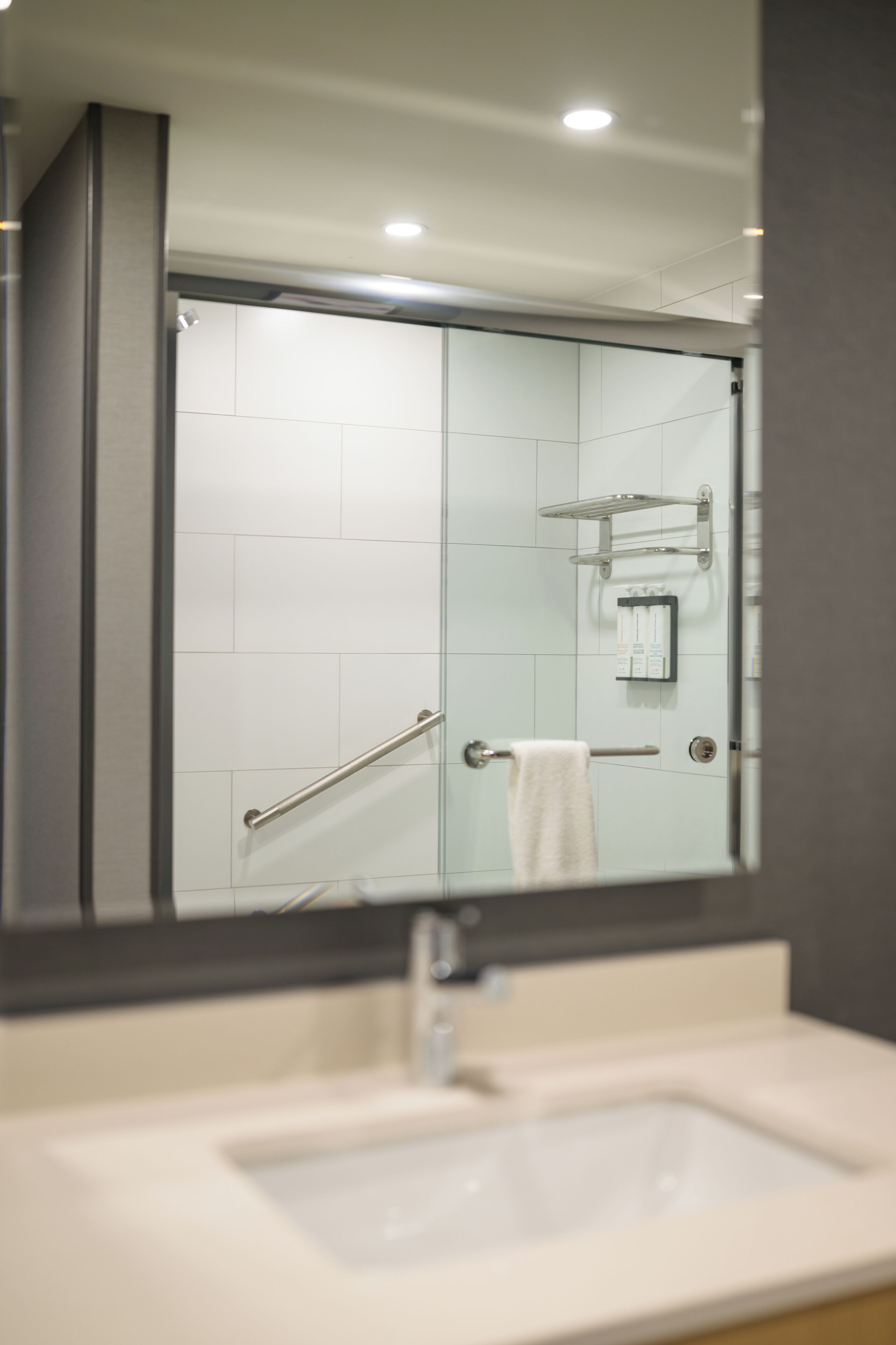 Ein modernes Badezimmer mit Duschkabine aus Glas, einem weißen Waschbecken und einem Handtuchhalter.