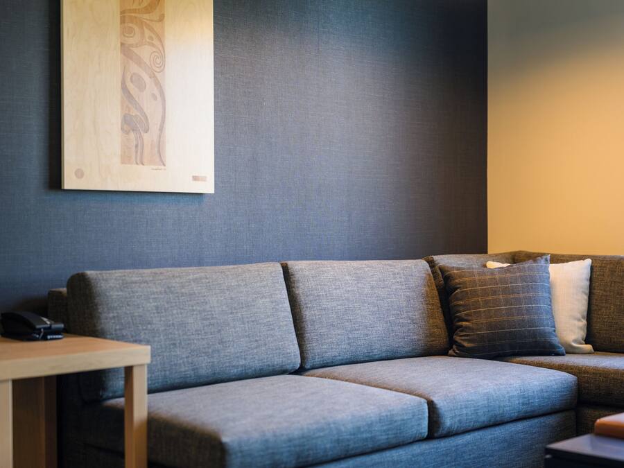 Una sala de estar moderna con un sofá gris, una mesita de madera y una lámpara colgante negra.