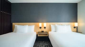 Habitación de hotel con dos camas, una pared oscura y dos lámparas fijadas a la pared.