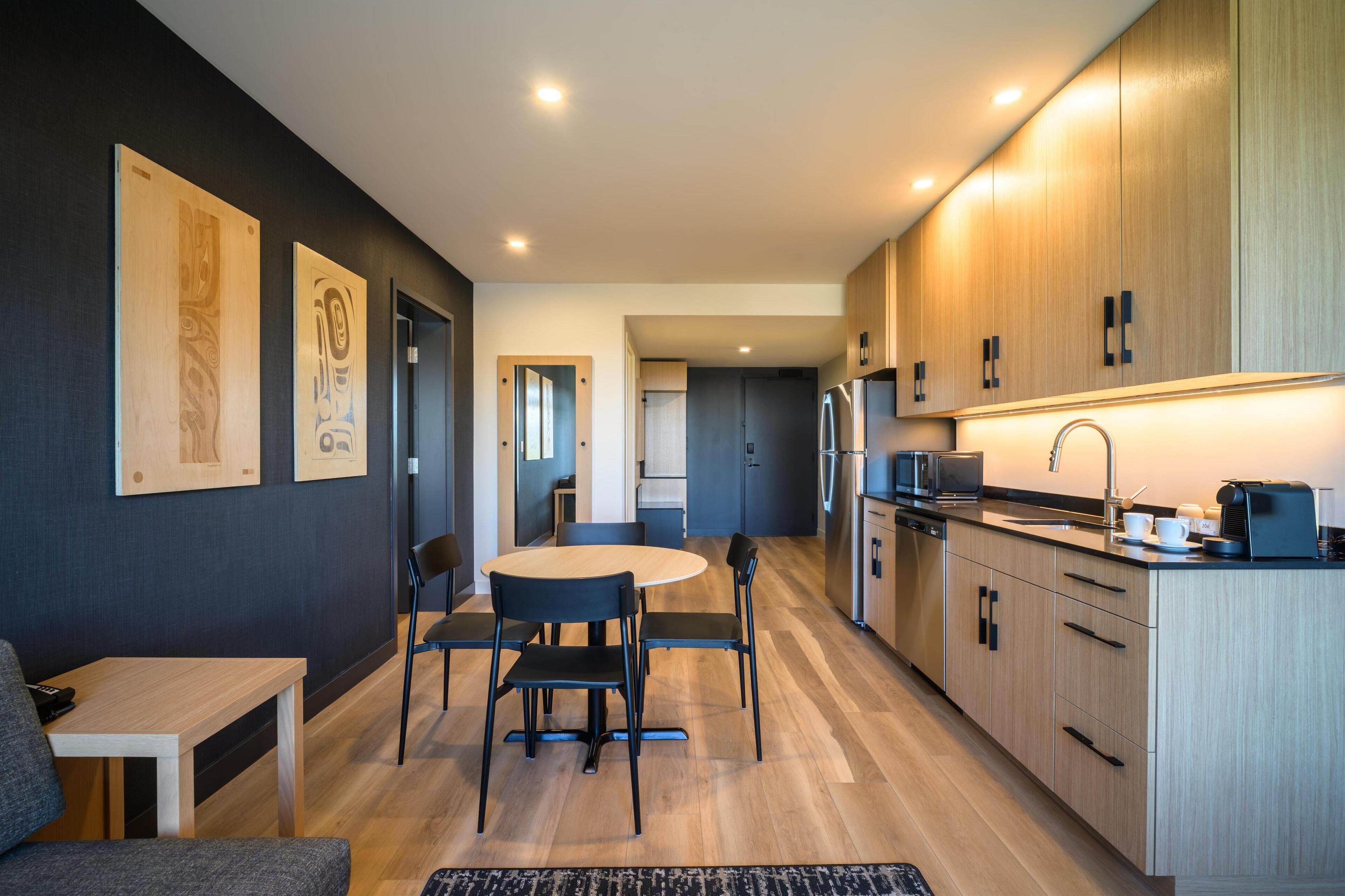 Eine moderne Küche mit Holzausstattung, einem Esstisch mit Stühlen und einem Kühlschrank.