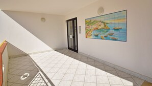 A hallway with tiled flooring, a door, and a painting of a coastal scene. - Three-room apartment Della Rosa Seaside Abruzzo (Alba Adriatica)
