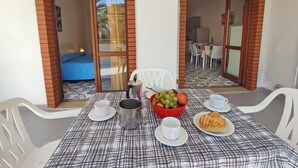 A dining area with a table set for two, a bowl of fruit, a pot, and a plate with a pastry. - Three-room apartment Della Rosa Seaside Abruzzo (Alba Adriatica)