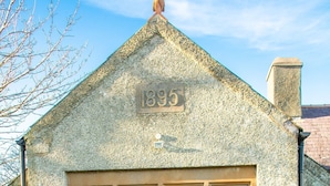 Un bâtiment en pierre doté d’une grande fenêtre et portant le numéro 1895 sur son mur.