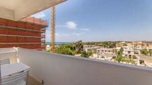 A balcony with a view of a coastal town, a construction crane, and a white table with chairs. - Sea View Apartment, Ac Gallipoli (Gallipoli)