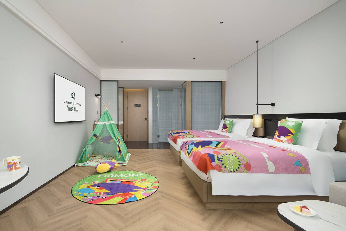 Ein modernes Hotelzimmer mit einem Bett, einem kleinen Tisch, einem Sessel, einem farbenfrohen Teppich und einer zeltartigen Konstruktion.