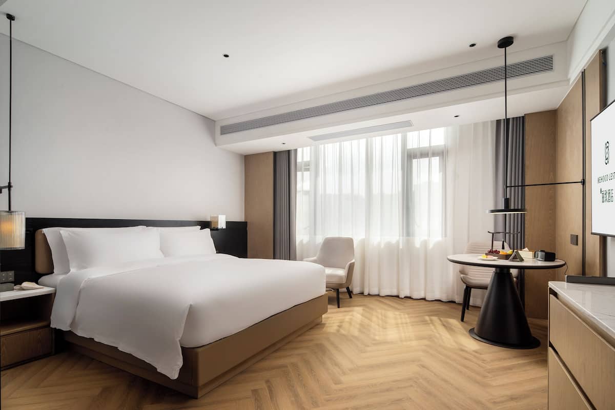 Ein modernes Hotelzimmer mit einem großen Bett, einem Schreibtisch, einem Stuhl und einem Esstisch.