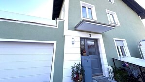 A two-story building with a garage door, a front door, and a small balcony. - Apartment 'Dandelion' with Private Terrace and Wi-Fi (Haag)