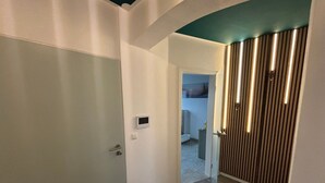 A hallway with a door, a wall-mounted control panel, and a radiator. - Apartment 'Dandelion' with Private Terrace and Wi-Fi (Haag)