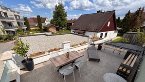 A patio with a table and chairs, a small garden area with plants, and a view of neighboring houses. - Apartment 'Dandelion' with Private Terrace and Wi-Fi (Haag)