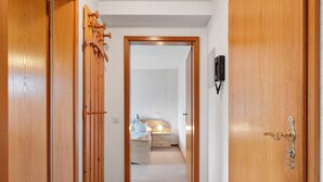 A hallway leading to a bedroom with a bed, bedside table, and a lamp. - Holiday Apartment 'Type B, 70sqm' with Mountain View, Private Terrace and Wi-Fi (Schluchsee)