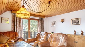 A living room with leather sofas, a wooden ceiling, a table with a board game, and a wooden cabinet with decorative items.