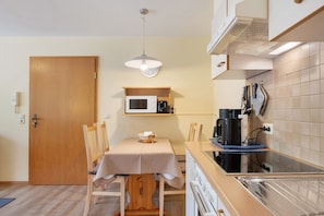 A compact kitchen with a microwave, coffee maker, and a wooden table with chairs.