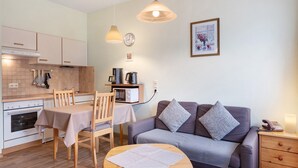 A compact kitchen with a dining area, a sofa, and a bedside table with a lamp. - Apartment '3 Kapelle' with Mountain View, Shared Terrace and Wi-Fi (Todtnau)