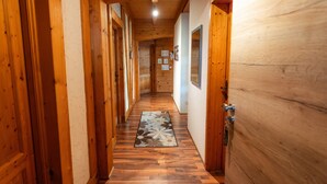 A wooden hallway with a patterned rug, wooden doors, and a ceiling light. - Apartment 'Monika' with Mountain View, Balcony and Wi-Fi (Schonach im Schwarzwald)