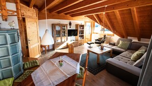A wooden interior with a dining table, sofa, and television. - Apartment 'Monika' with Mountain View, Balcony and Wi-Fi (Schonach im Schwarzwald)