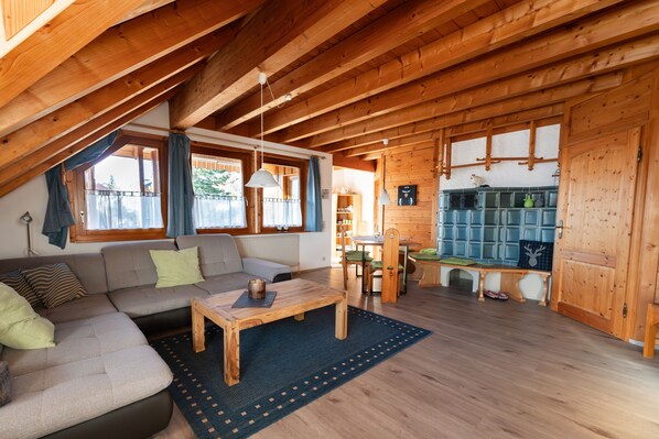 A cozy wooden cabin with a loft bedroom, a living area with a sofa and coffee table, and a kitchen area.