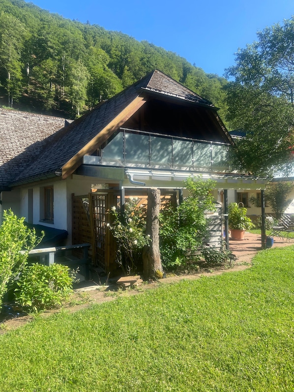 Un chalet traditionnel doté d’un toit en pente, d’une terrasse en bois et d ’un mur en pierre.