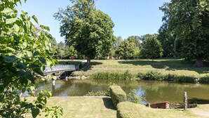 A park with a pond, a bridge, and neatly trimmed hedges. - Apartment 'Schloss Glücksburg' with Lake View, Private Garden and Wi-Fi (Glücksburg (Ostsee))
