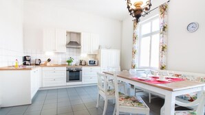 A modern kitchen with white cabinets, a wooden countertop, and a dining area with a table and chairs. - Apartment 'Schloss Glücksburg' with Lake View and Wi-Fi (Glücksburg (Ostsee))