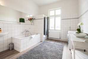 A modern bathroom with a bathtub, a sink, a toilet, and a window. - Apartment 'Schloss Glücksburg' with Lake View and Wi-Fi (Glücksburg (Ostsee))