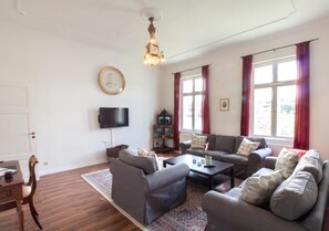 A living room with two sofas, a coffee table, a TV, and a bookshelf. - Apartment 'Schloss Glücksburg' with Lake View and Wi-Fi (Glücksburg (Ostsee))