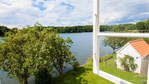 A lakeside view with a white building, a tree, and a clear sky. - Apartment 'Schloss Glücksburg' with Lake View and Wi-Fi (Glücksburg (Ostsee))