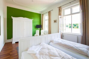 A room with two beds, a white wardrobe, a television, and a window with curtains. - Apartment 'Schloss Glücksburg' with Lake View and Wi-Fi (Glücksburg (Ostsee))