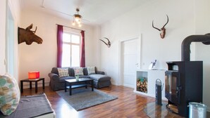 A living room with a sofa, coffee table, fireplace, and mounted animal heads. - Apartment 'Schloss Glücksburg' with Lake View and Wi-Fi (Glücksburg (Ostsee))