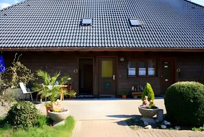 Een gebouw met een pannendak, een voordeur en bloempotten.
